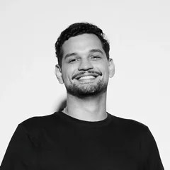 Luís Victor Quintas sorrindo, de camiseta preta, em foto preto e branco.